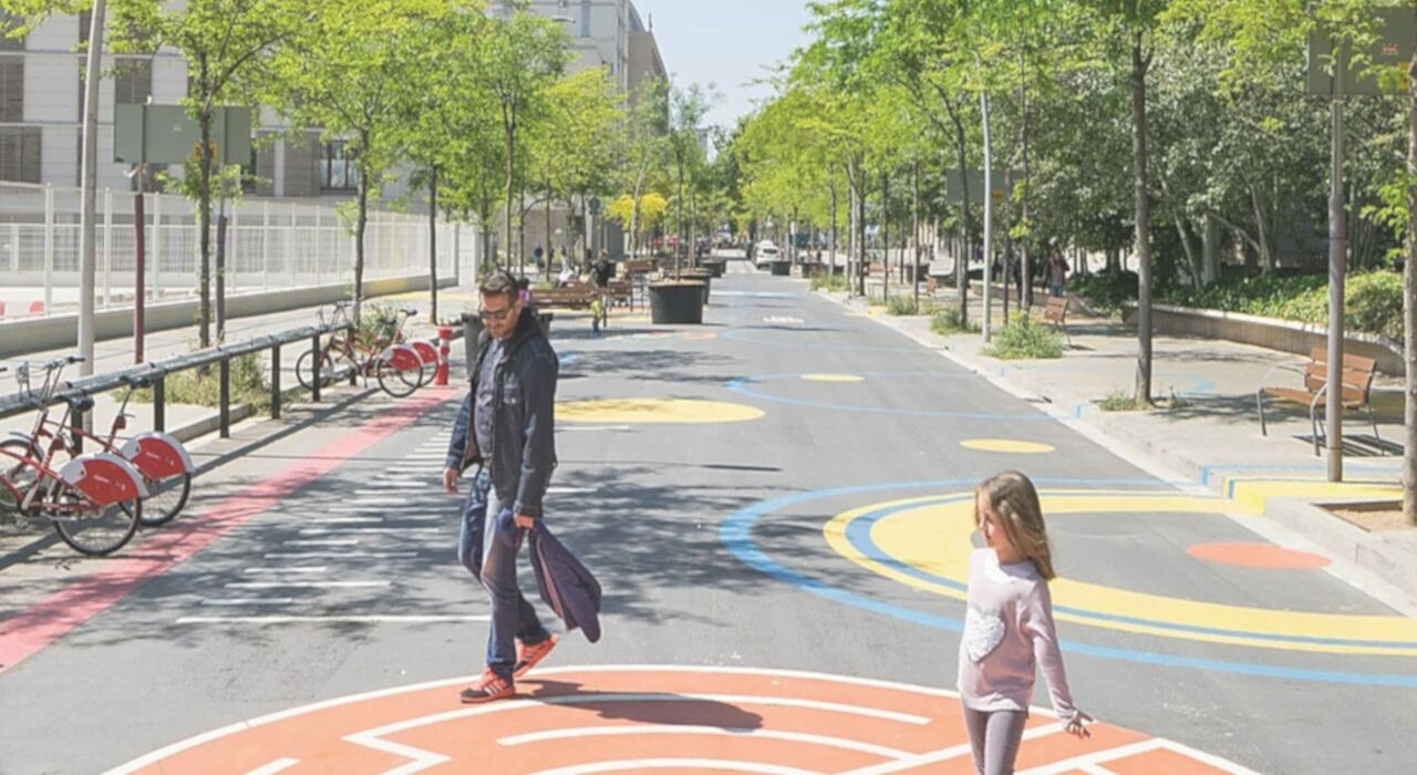 Superblock in Barcelona. Vater und Tochter laufen über eine verkehrsberuhigte Straße mit bunten Straßenmalereien und Hüpfspielen